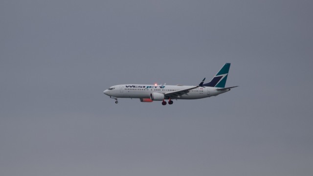 WestJet airliner with red light glowing along the engine and undercarriage
