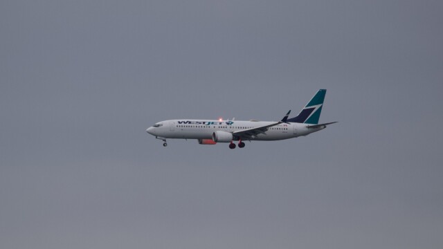 WestJet airliner with red light glowing along the engine and undercarriage